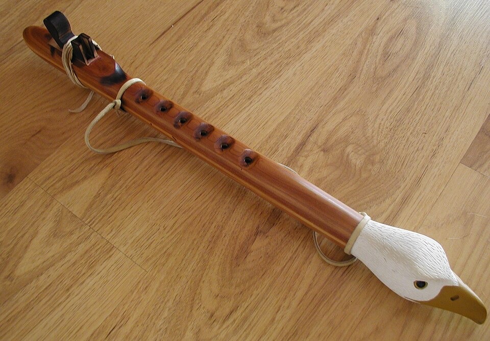 A wooden Native American flute with a carved bird-shaped block near the mouthpiece