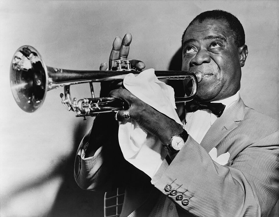 Louis Armstrong playing the trumpet, looking up, a handkerchief in his hand