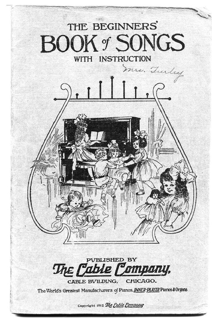 Cover of The Beginners' Book of Songs with Instruction, 1912: children around a piano inside a drawing of a lyre