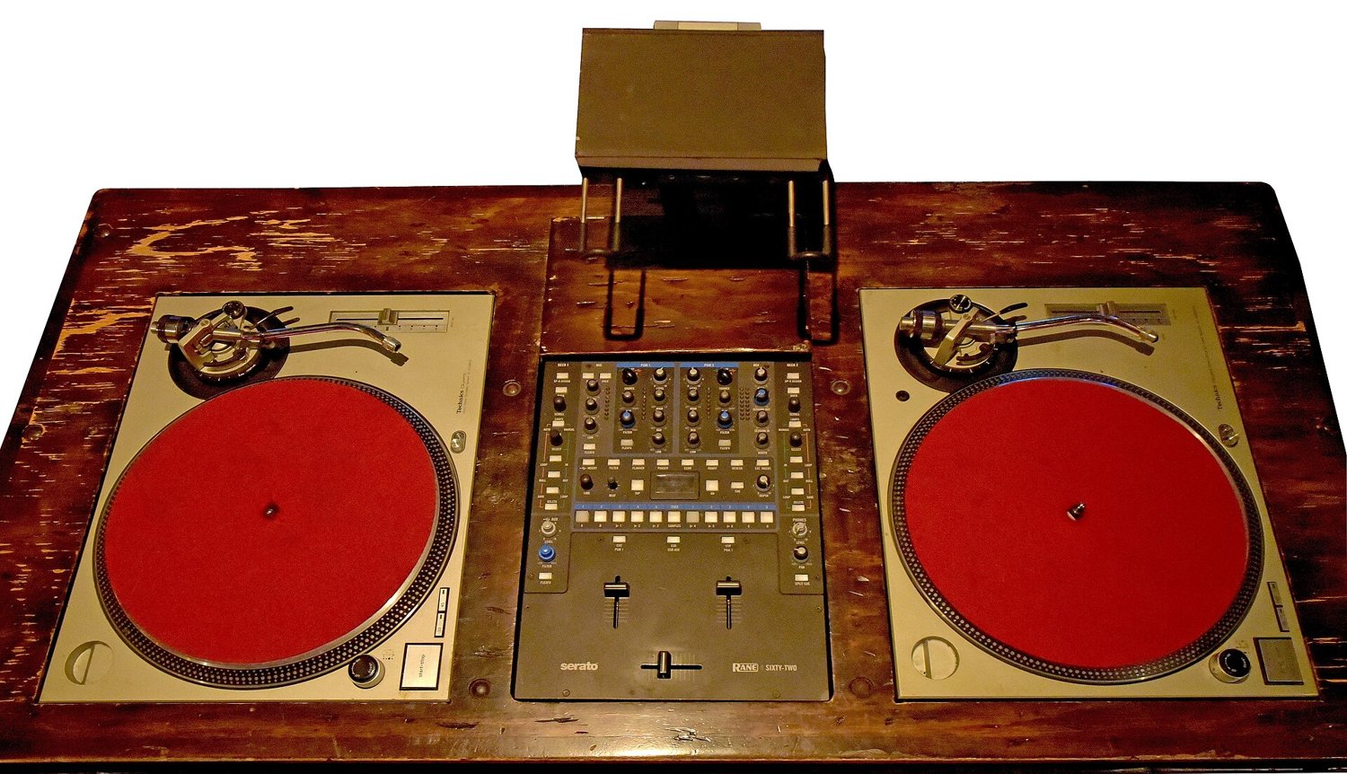 Two silver turntables with red mats on a wooden table, a DJ mixer between them
