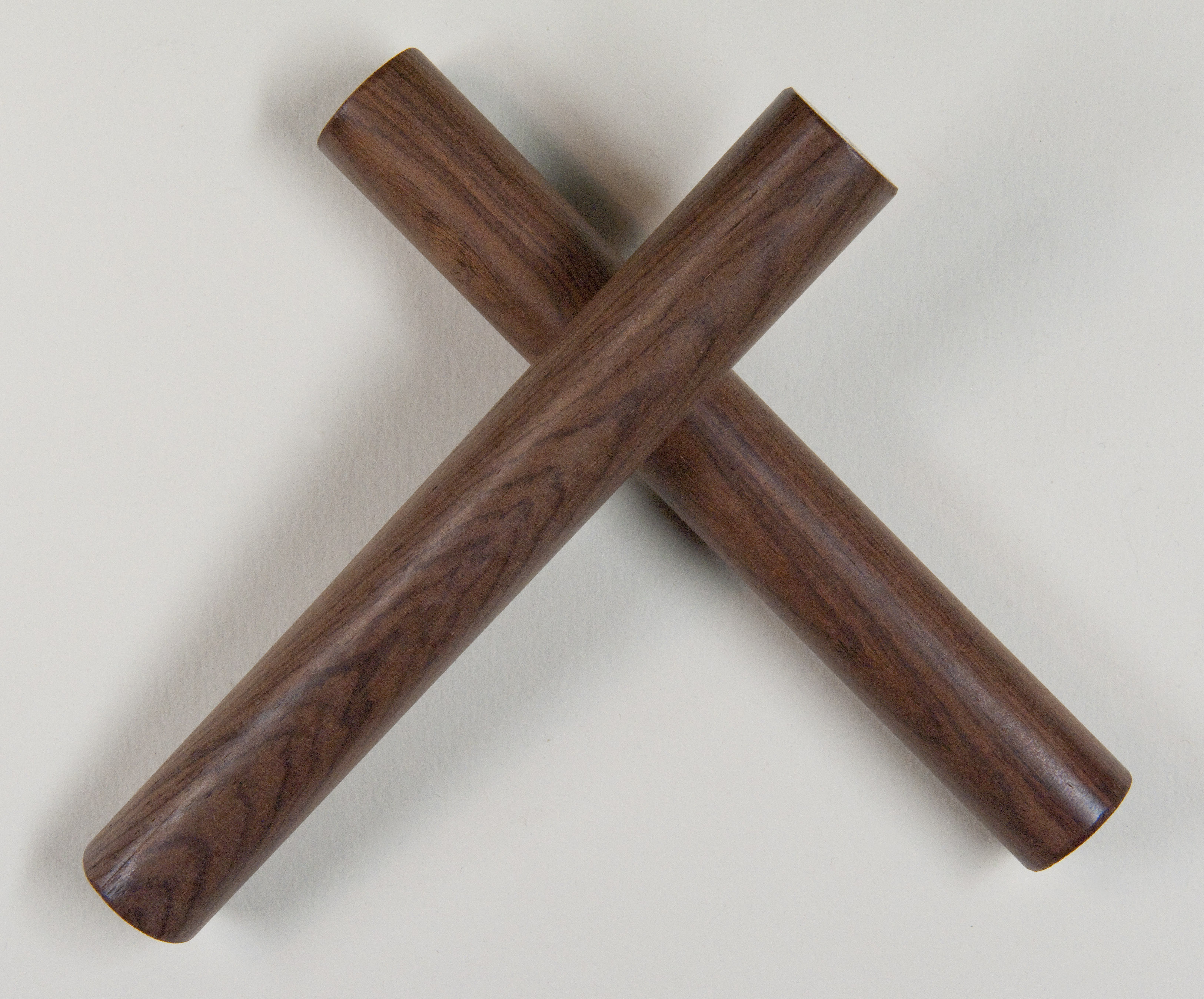 A pair of wooden claves — two short cylindrical sticks used as a percussion instrument